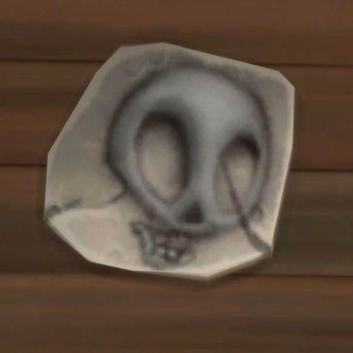 A screenshot from The Sims 4 showing a rock on the ground. On the rock is an image of a weirdly shaped skull