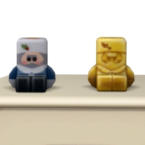A screenshot from the sims 4 the top of a table with two Simmies on top. The one is gold and the other is a regular Father Winter Simmi