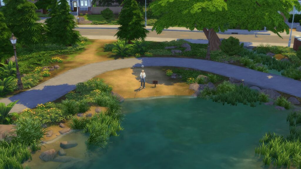 A screenshot from The Sims 4 showing a fishing spot on some sand in a pond with a curved path way
