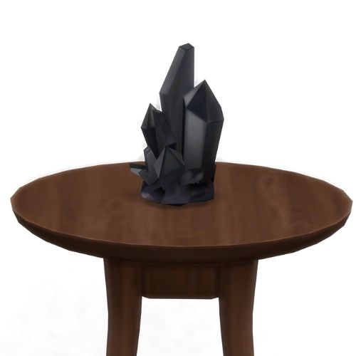 A screenshot from The Sims 4 showing a brown circular table with a crystal on top. This image has a crystal called hematite