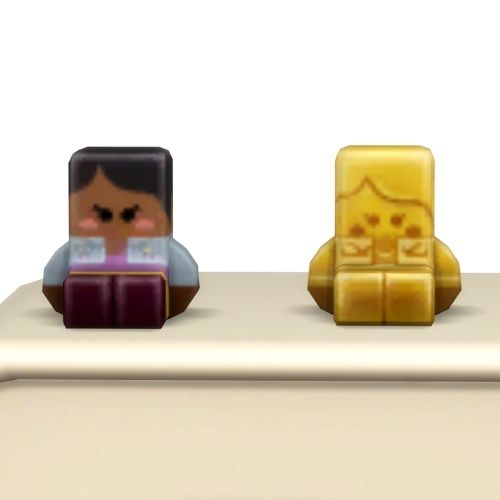 A screenshot from the sims 4 the top of a table with two Simmies on top. The one is gold and the other is a regular Jasmine Holiday Simmi