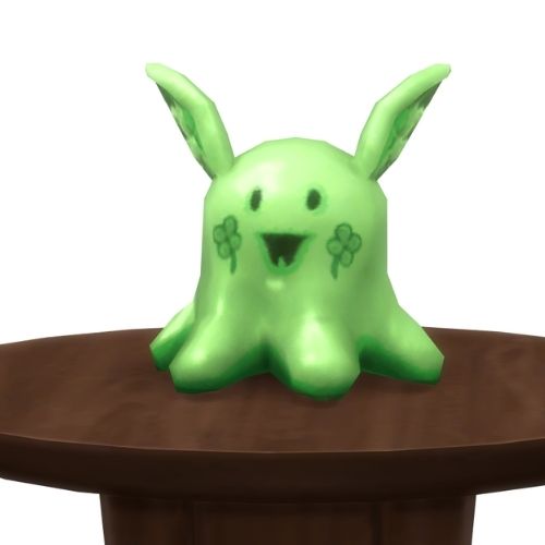 A screenshot from The Sims 4 showing a round, brown table with a Meduso Plushie on top that's green with clovers on the cheeks