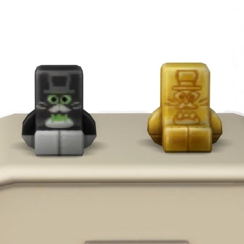 A screenshot from the sims 4 the top of a table with two Simmies on top. The one is gold and the other is a regular Mayor Whiskers Simmi