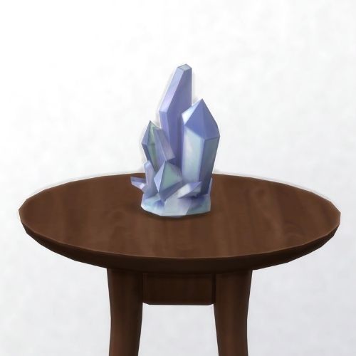 A screenshot from The Sims 4 showing a brown circular table with a crystal on top. This image has a crystal called simanite