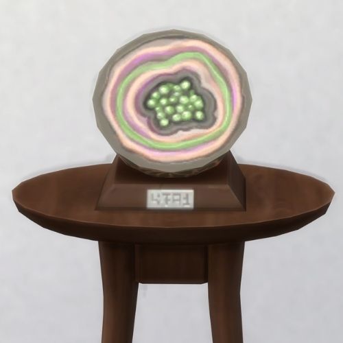 A screenshot from The Sims 4 with a brown table and on top is the geode named Zarinne