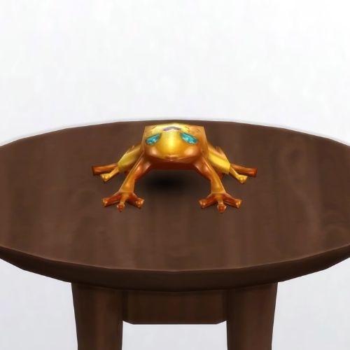 A screenshot from The Sims 4 showing a brown circle table and on top is a golden frog with blue eyes