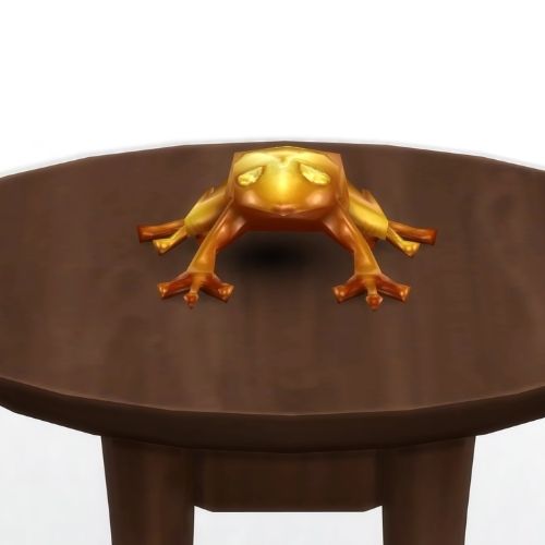 A screenshot from The Sims 4 showing a brown circle table and on top is a golden frog with yellow eyes