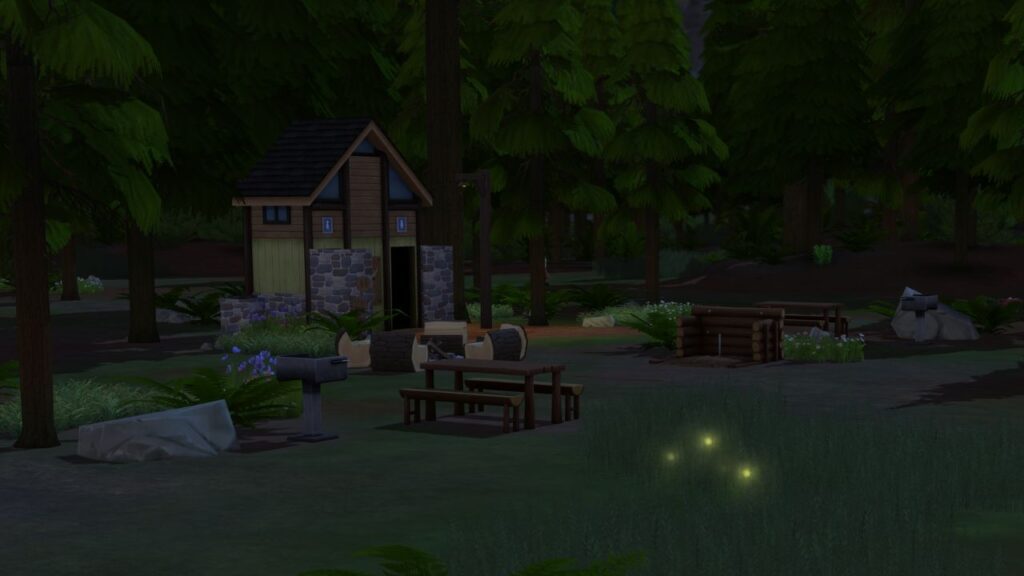 A screenshot from The Sims 4 showing some fireflies near a picnic area and bathroom in a forest