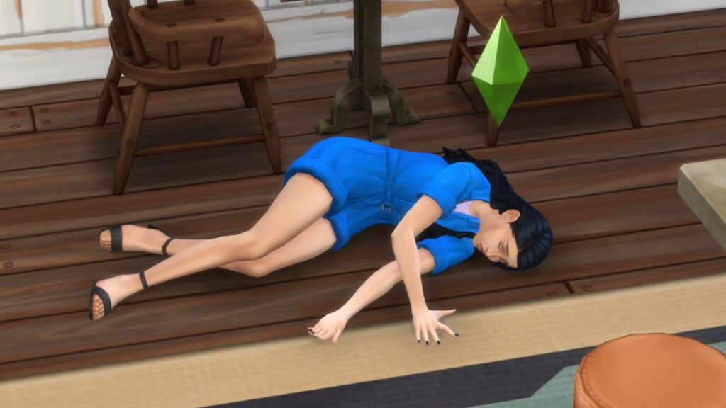 A screenshot from The Sims 4 showing a sim laying on the ground in a blue jumpsuit 